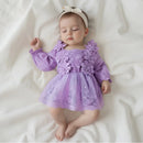 Bebê dormindo vestindo vestido lilás com bordados florais e faixa de cabelo branca